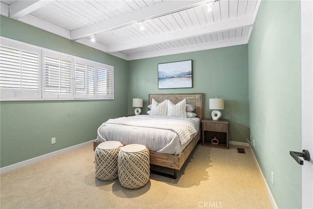 carpeted bedroom with visible vents, rail lighting, beam ceiling, and baseboards