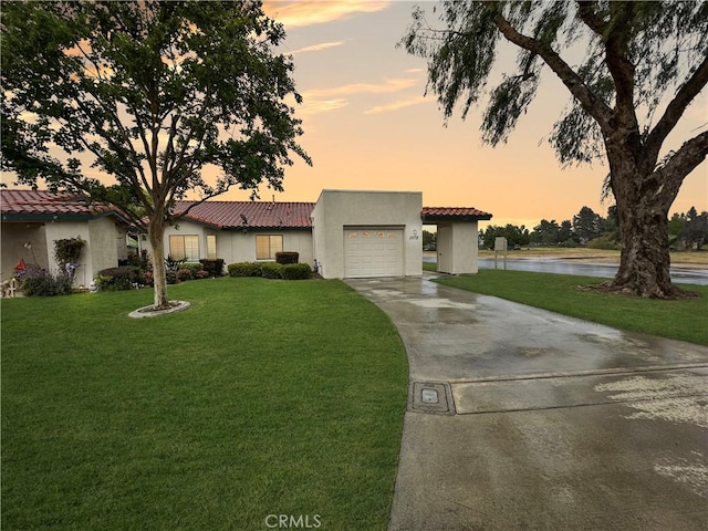 view of front of property featuring a lawn, an attached garage, a water view, and driveway