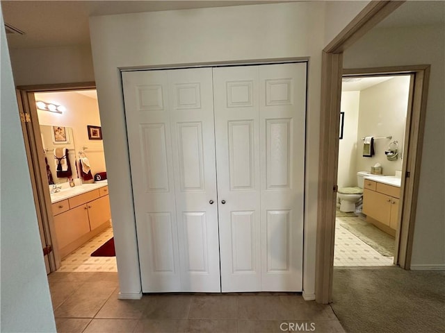 unfurnished bedroom with connected bathroom, light tile patterned floors, and a closet