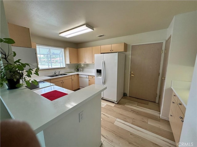 kitchen featuring light brown cabinetry, a sink, white appliances, light wood-type flooring, and visible vents
