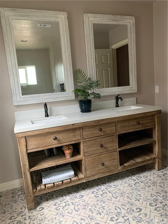 bathroom featuring visible vents, double vanity, and a sink