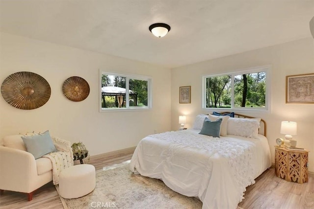 bedroom with baseboards, wood finished floors, and multiple windows
