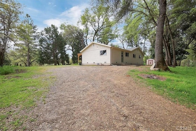 view of front of home featuring driveway, a storage shed, board and batten siding, and an outdoor structure