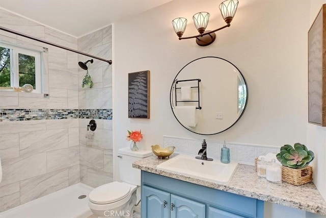 bathroom with tiled shower, toilet, and vanity