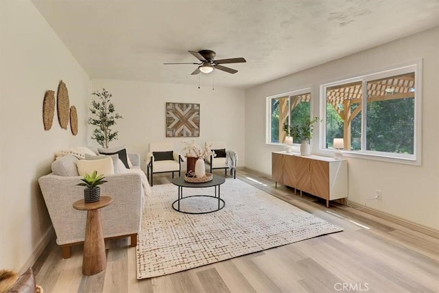 living area featuring a ceiling fan, wood finished floors, and baseboards