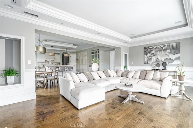 living room with crown molding, a tray ceiling, and wood finished floors