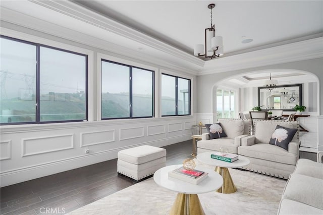 living room featuring an inviting chandelier, arched walkways, ornamental molding, and wood finished floors