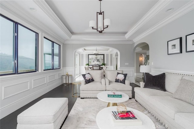 living room with an inviting chandelier, a decorative wall, wood finished floors, a wainscoted wall, and arched walkways