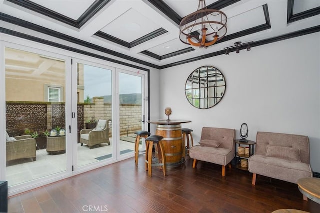 sitting room featuring crown molding, coffered ceiling, wood finished floors, and a chandelier
