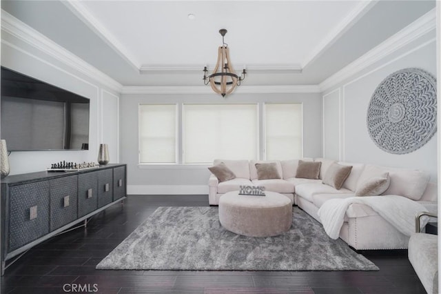 living area with an inviting chandelier, crown molding, a tray ceiling, and wood finished floors
