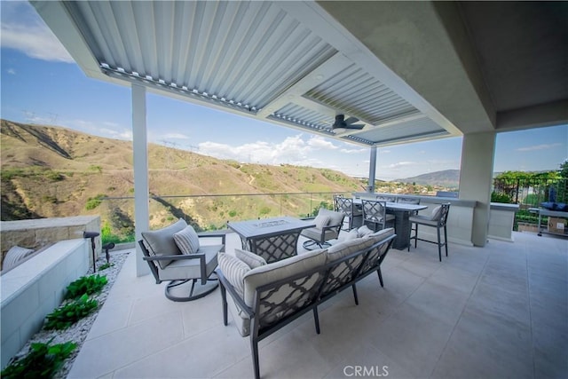 view of patio with a ceiling fan, a mountain view, and an outdoor living space