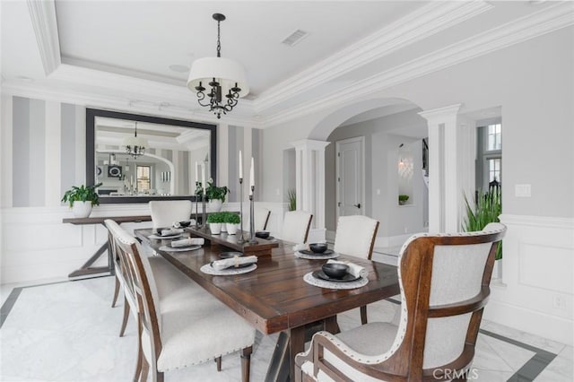 dining room with visible vents, arched walkways, wainscoting, ornamental molding, and a decorative wall