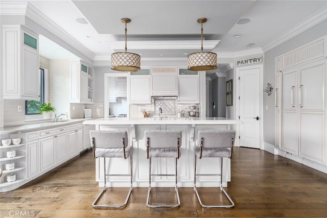 kitchen featuring a breakfast bar area, tasteful backsplash, open shelves, light countertops, and white cabinets