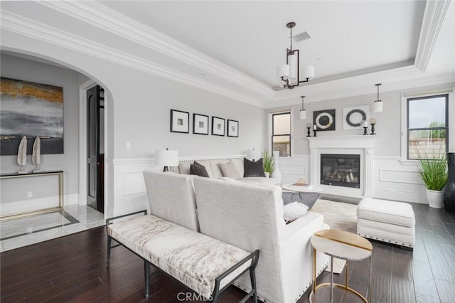 living room featuring visible vents, a raised ceiling, wood finished floors, and a healthy amount of sunlight