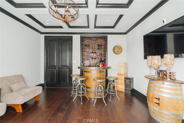 bar with wood finished floors, a bar, a chandelier, ornamental molding, and coffered ceiling