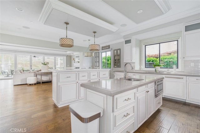 kitchen featuring light countertops, crown molding, an island with sink, and a sink