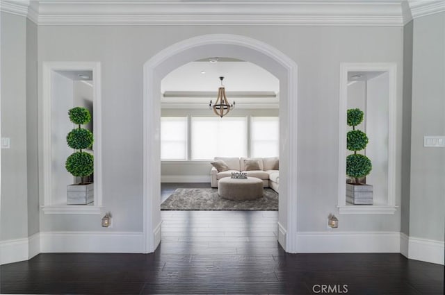 hall with crown molding, wood finished floors, baseboards, a chandelier, and arched walkways
