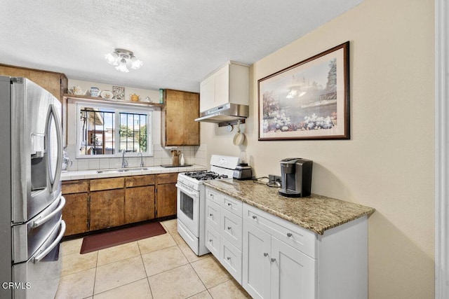kitchen featuring white gas stove, light countertops, under cabinet range hood, stainless steel fridge with ice dispenser, and a sink
