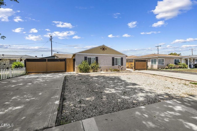ranch-style home with fence, stucco siding, and concrete driveway