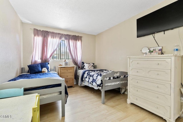 bedroom with light wood-type flooring and a textured ceiling