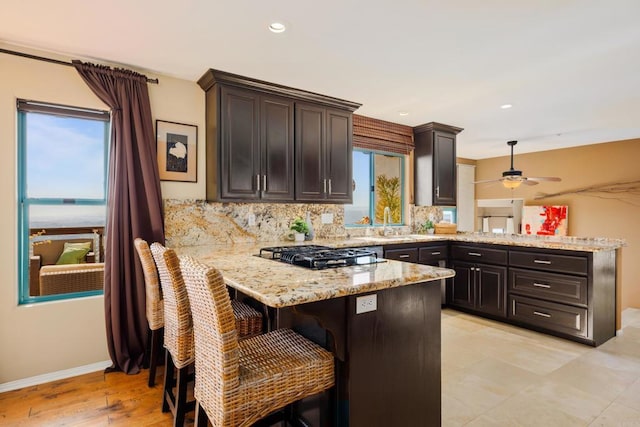 3351 Red Mountain Heights Dr, Fallbrook, CA 92028 - kitchen featuring a peninsula, ceiling fan, light stone counters, backsplash, and black gas cooktop