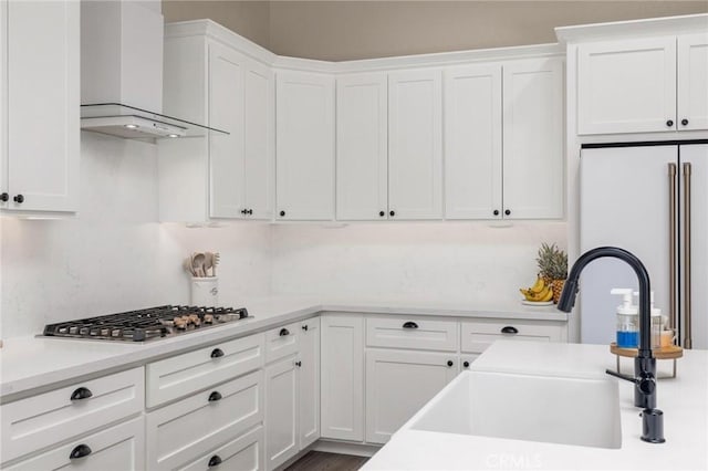 kitchen with a sink, white cabinetry, stainless steel gas stovetop, and wall chimney exhaust hood