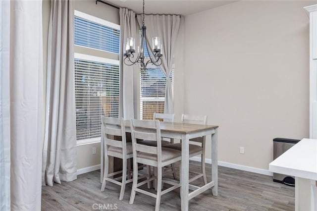 dining area with an inviting chandelier, light wood-style floors, and baseboards
