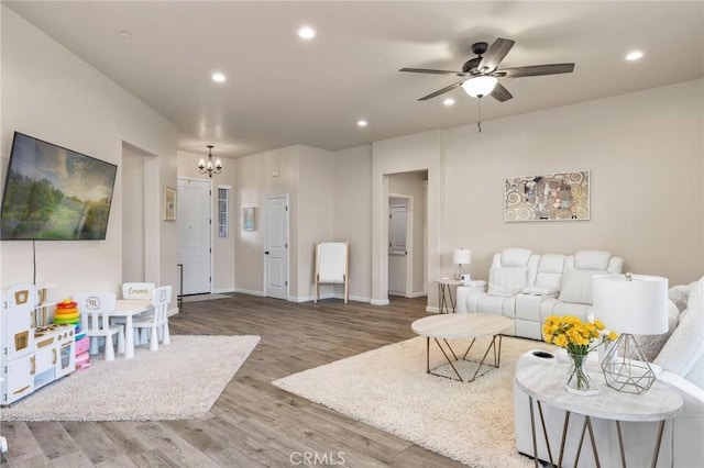 living room with recessed lighting, baseboards, wood finished floors, and ceiling fan with notable chandelier