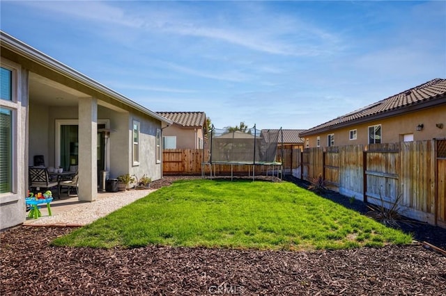 view of yard with a patio, a trampoline, and a fenced backyard