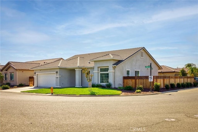 view of front of property featuring stucco siding, fence, a tile roof, driveway, and an attached garage