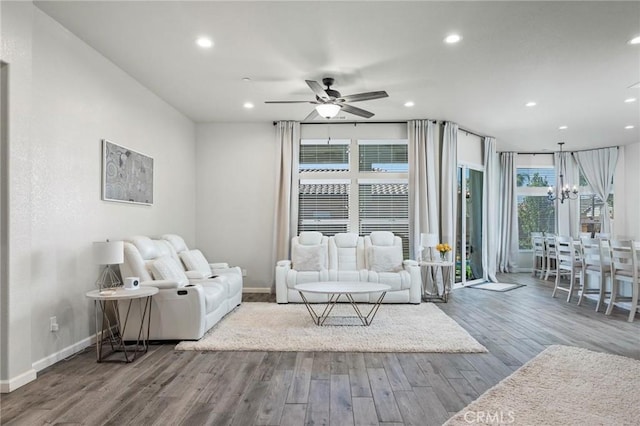 living room with recessed lighting, ceiling fan with notable chandelier, wood finished floors, and baseboards