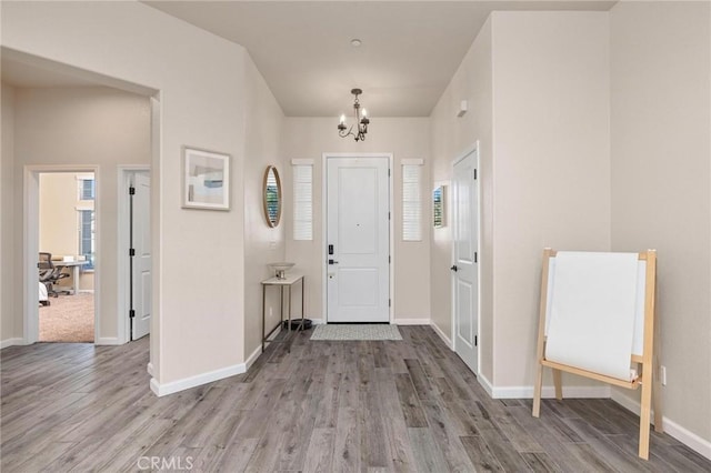 foyer entrance with a notable chandelier, wood finished floors, and baseboards