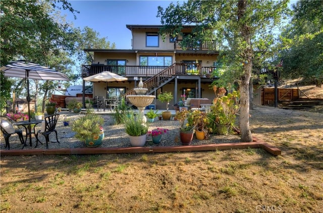 back of house featuring fence, a deck, stairs, and a patio