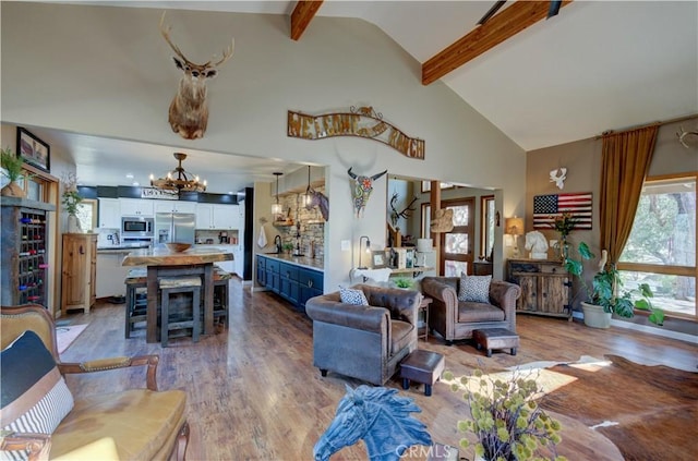 living area featuring light wood-type flooring, high vaulted ceiling, a notable chandelier, and beamed ceiling