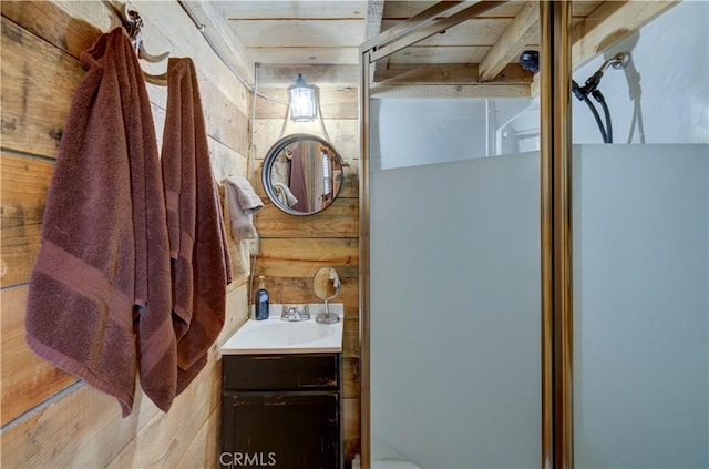 bathroom featuring wood walls, a shower with shower door, and vanity