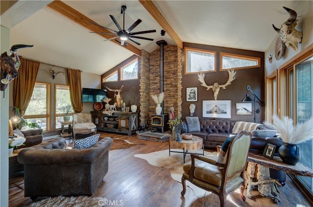 living room with wood finished floors, ceiling fan, beam ceiling, a wood stove, and high vaulted ceiling