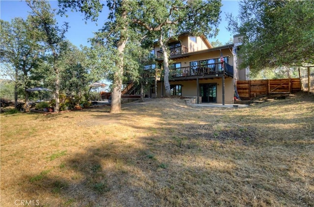 back of property featuring a wooden deck, a yard, and fence