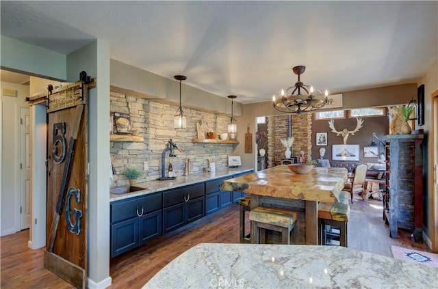 kitchen featuring a chandelier, light stone countertops, a barn door, and dark wood finished floors
