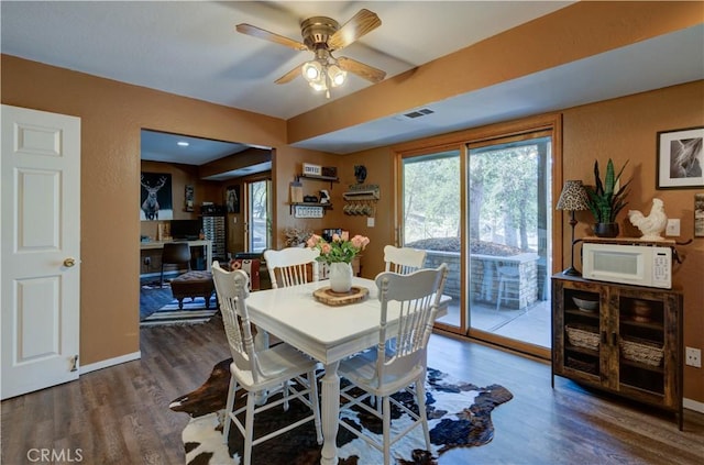 dining room featuring baseboards, visible vents, wood finished floors, and ceiling fan