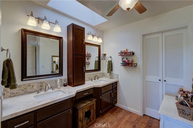 bathroom with double vanity, wood finished floors, a ceiling fan, and a sink