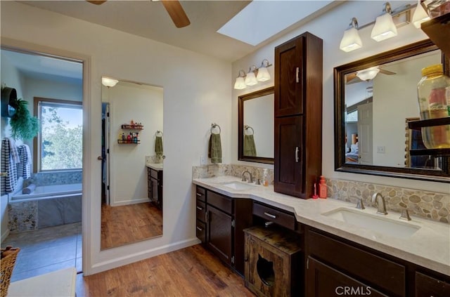 full bathroom with a skylight, a sink, and ceiling fan