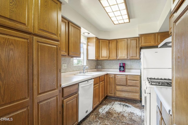 kitchen featuring brown cabinets, white appliances, tasteful backsplash, and a sink