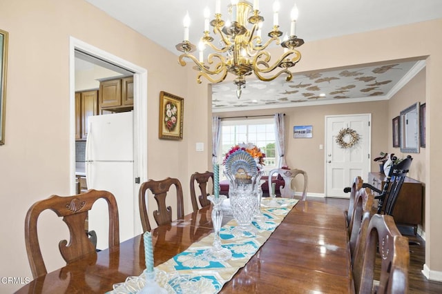 dining space with baseboards, dark wood finished floors, an inviting chandelier, and crown molding