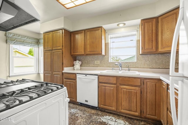kitchen with a sink, brown cabinetry, white appliances, wall chimney exhaust hood, and light countertops