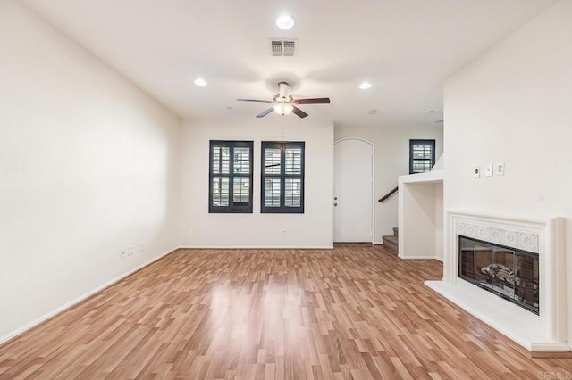 unfurnished living room featuring visible vents, a ceiling fan, light wood-style flooring, and a wealth of natural light