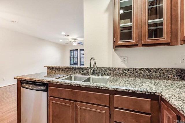 kitchen featuring a ceiling fan, glass insert cabinets, light wood-style floors, a sink, and dishwasher