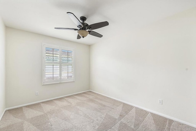 carpeted empty room featuring a ceiling fan and baseboards