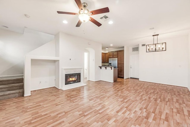 unfurnished living room featuring light wood-style floors, ceiling fan with notable chandelier, recessed lighting, and visible vents