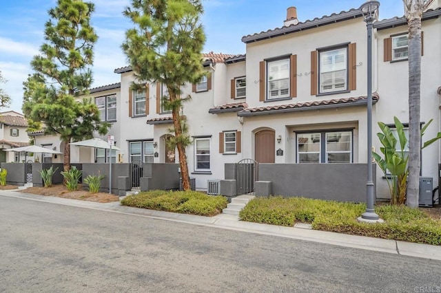 view of front of home with a tiled roof, fence private yard, a gate, and stucco siding