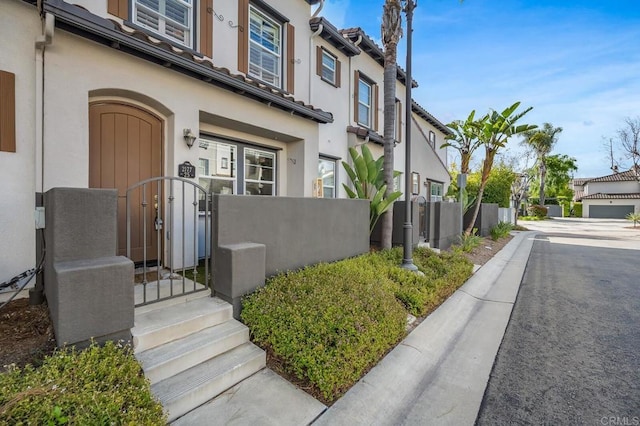 doorway to property featuring fence, a gate, stucco siding, and a residential view